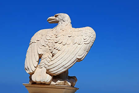 White stone eagle guards the gate to Bahai Gardens over blue sky in Haifa, Israelの写真素材