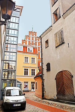Medieval street in old Riga, Latvia. View of Saint John's Church (red bulding) andold industrial...