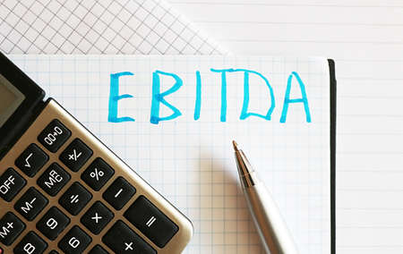 The word EBITDA is written by hand on the paper. Concept of financeの写真素材