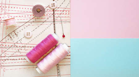 Multicolored thread coils on color background. Sewing supplies, pattern and accessories for...