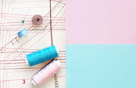 Multicolored thread coils on color background. Sewing supplies, pattern and accessories for...