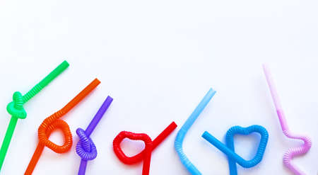 Isolated colour plastic cocktail tubes with a flexible part, due to which they can be twisted into a knot or in a zigzag, or a heart shape, on a white background. Copy space. Eco concept. Bannerの写真素材