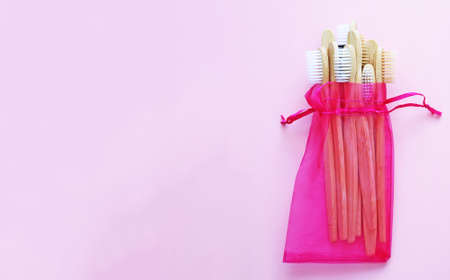 Bamboo toothbrushes  in crimson pouch that is reusable on trendy pink background. Eco-friendly products. Eco, zero waste and health concepts. Flat lay. Place for text. Biodegradable material. Bannerの写真素材