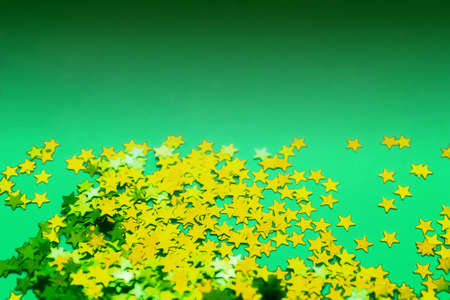 Green paper background with golden glitter stars. Flat lay. Holiday concept. New year time. Dimming effectの写真素材