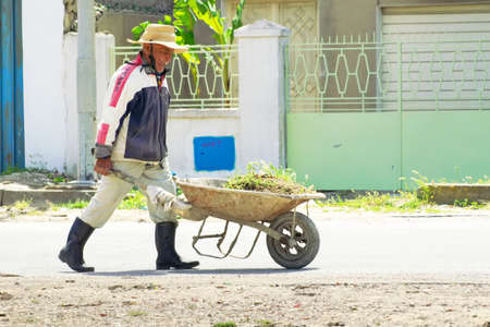 BIZERTE, TUNISIA - MAY 08, 2007: Tunisian pushes a small cart with ground and grassのeditorial素材