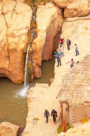 SAHARA, TUNISIA - MAY 1, 2008: Swimmer jumped into the water in a narrow gorge in northern Sahara. People stand on the edge of the cliff and look for itのeditorial素材