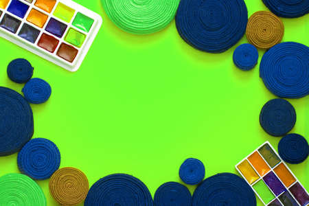 Rolls of fabric stripes and a watercolor paints on a green background as a frame. The fabric stripes are made of old wears. The concept of upcycling and zero waste. の写真素材