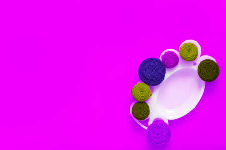 Paint palette with rolls of fabric stripes as a paint on a magenta background. The fabric stripes are made of old wears. The concept of upcycling and zero waste.の写真素材