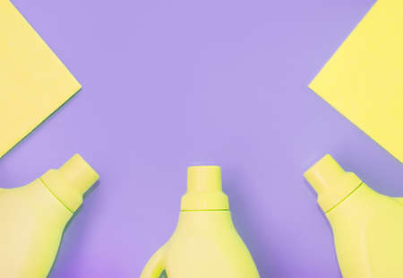 Yellow plastic bottles with chemicals for cleaning, rags for cleaning. Purple background. Cleaning conceptの写真素材