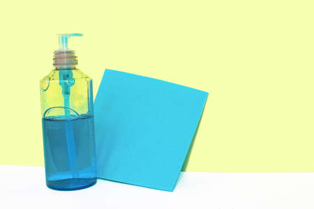 Bottle with blue liquid and a blue rag for cleaning against a yellow wall. Cleaning conceptの写真素材
