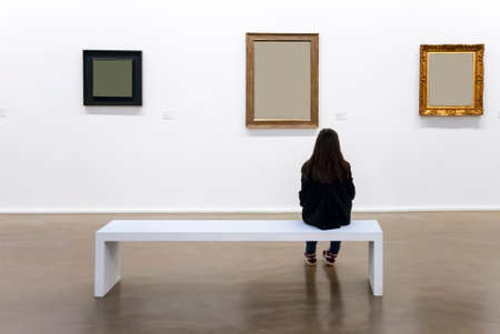 lonely girl in the gallery in front of paintingsの写真素材