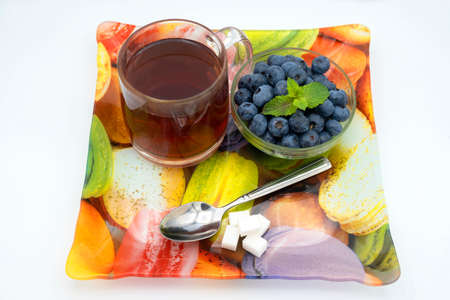 ripe juicy and tasty blueberries on a board with a cup of aromatic black tea