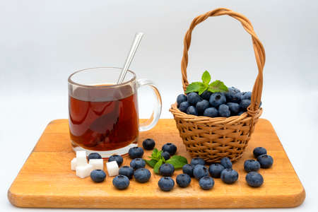 ripe juicy and tasty blueberries on a board with a cup of aromatic black tea