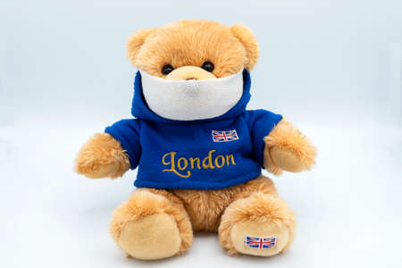 teddy bears from different countries wearing protective masks against coronavirus on a white...