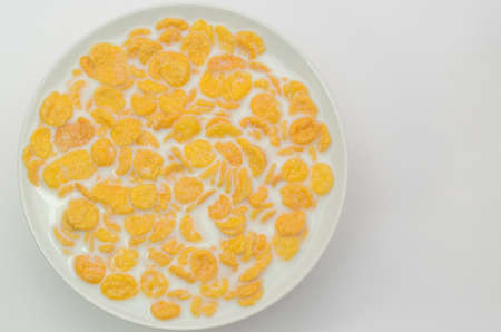 Cornflakes with milk on a spoon in a bowl on a light background.の写真素材