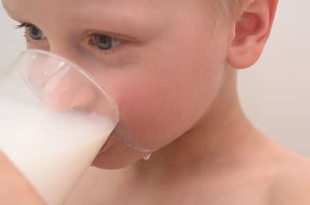 The boy drinks milk from a glass for breakfast.の写真素材