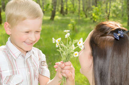 The boy gives flowers to his mother.の写真素材