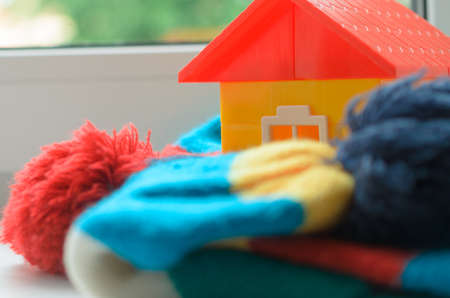 Toy house on the window sill wrapped in a scarf. Warming up the house.の写真素材
