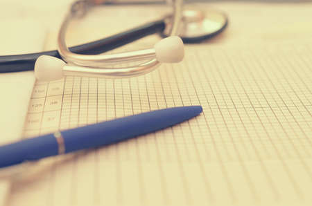 A phonendoscope lies on the doctors desk along with a pen, a history of the disease and ampoules with a medicine.の写真素材