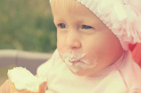 A little girl is eating ice cream and smeared her face.の写真素材