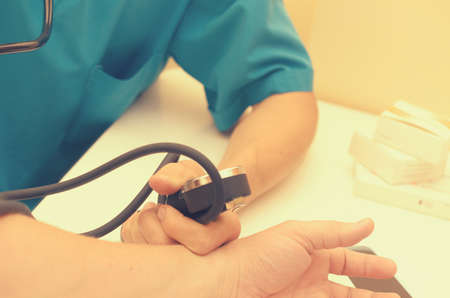 The doctor measures the pressure with a phonendoscope