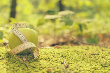 Green apple on green grass with measuring tape and withoutの写真素材