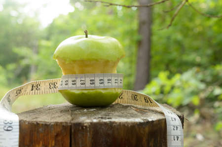 A green apple with a green ribbon and a measuring tapeの写真素材