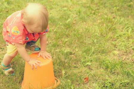 Little girl is playing with an empty bucket