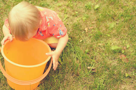 Little girl is playing with an empty bucketの写真素材