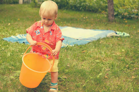 Little girl is playing with an empty bucketの写真素材