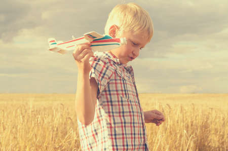 The boy with his hand runs the model of the plane into the skyの写真素材