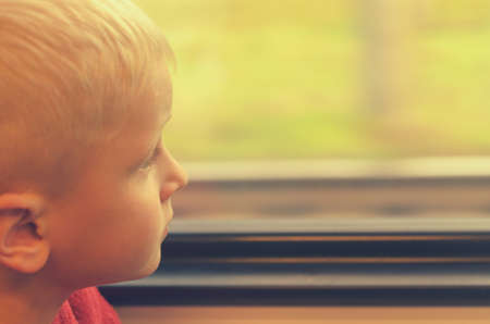 The boy looks out the window of the train carの写真素材