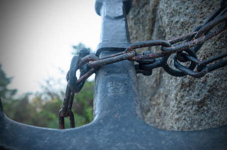 A statue of a large metal anchor, chained to a stoneの写真素材