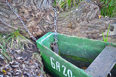 The old boat is tied to a tree trunk by a chainの写真素材