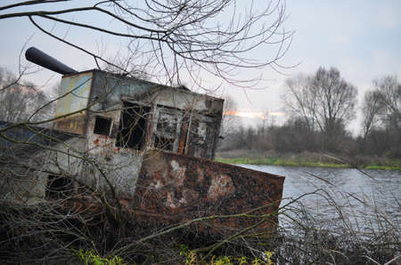 A dilapidated barge moored on the river bankの写真素材