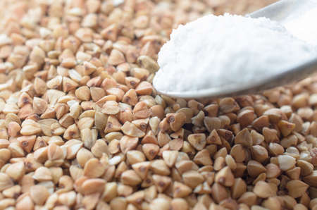 Buckwheat groats strewn on the surface and a spoonful of saltの写真素材