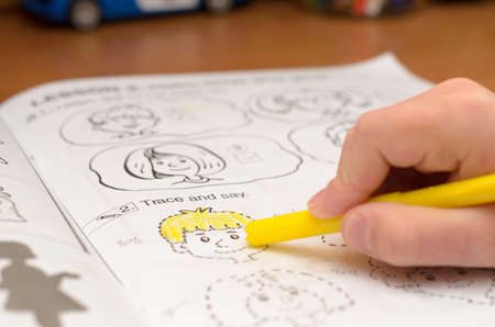 A child's hand writes and displays English letters in a notebook and alphabet with a pencil and felt-tip penの写真素材