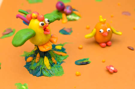 Rooster and chicken from plasticine on a yellow backgroundの写真素材
