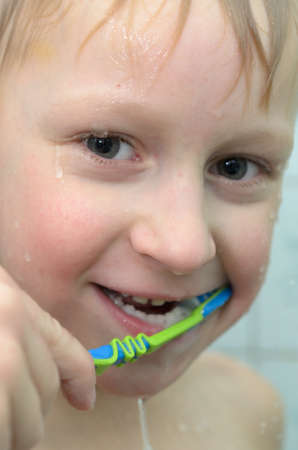 A teenager boy in the shower is brushing his teethの写真素材