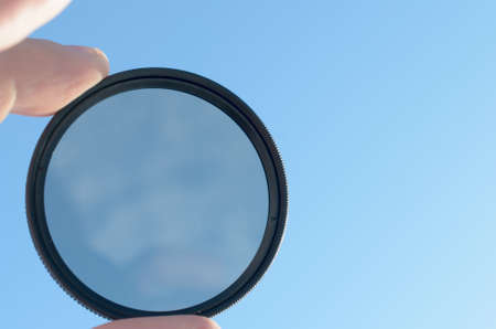 Fingers hold the photo filter against the blue skyの写真素材