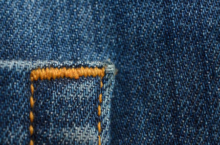 Textile texture of blue jeans with orange stitching