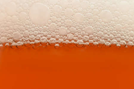 Bubbles from a beer froth close-up on half a glassの写真素材