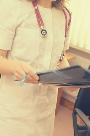 A radiologist with a stethoscope on the neck is watching an x-ray of an orthopedic patientの写真素材