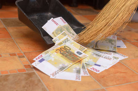 Broom sweep a lot of dollar and euro bills in the scoop.