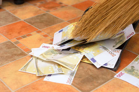 Broom sweep a lot of dollar and euro bills in the scoop.の写真素材