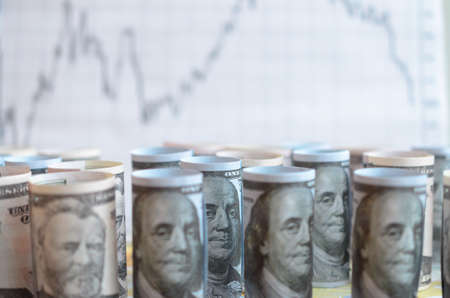 A lot of twisted dollar bills on the background of financial charts