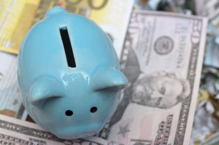 Blue piggy bank on a lot of money bills