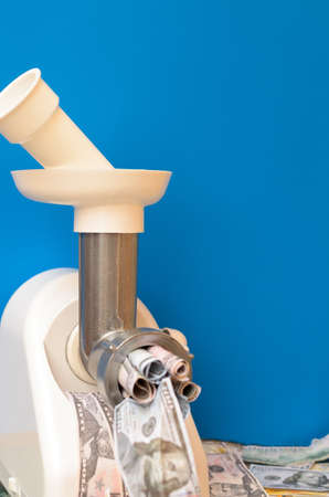 Money passes through a meat grinder. Blue background