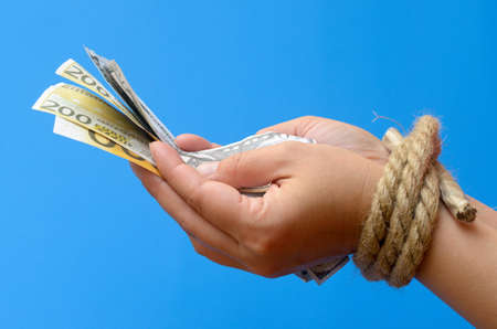 Women's hands tied with a rope and holding money. Credit bondage