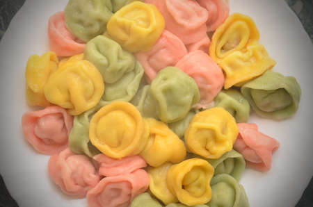 Multicolored ravioli for a festive menu are cooked in a pan and on a plateの写真素材